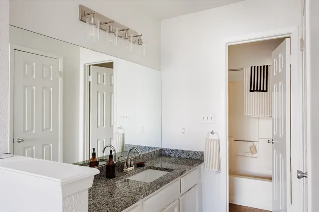 a bathroom with a granite countertop sink and a mirror