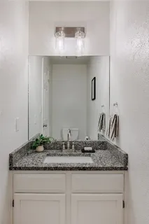 a bathroom with a granite countertop sink and a mirror
