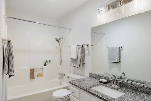 a bathroom with a granite countertop sink toilet and shower
