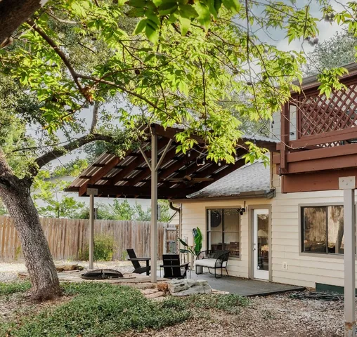 a view of a patio with table and chairs under an umbrella with a tree