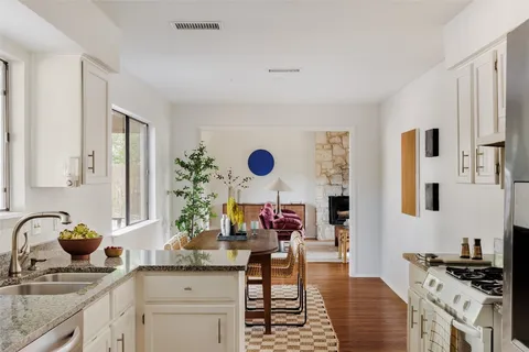 a kitchen with stainless steel appliances kitchen island granite countertop a sink stove and white cabinets