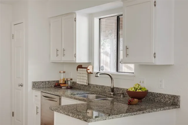 a kitchen with granite countertop a sink a stove and cabinets