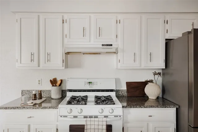 a kitchen with white cabinets and appliances