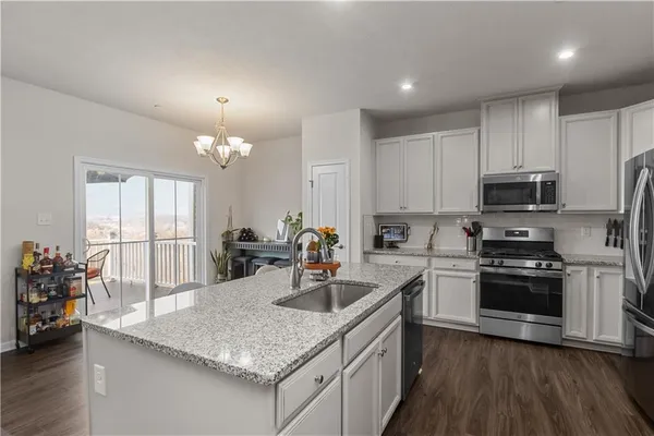 a kitchen with stainless steel appliances granite countertop a sink dishwasher a stove and a refrigerator with wooden floor