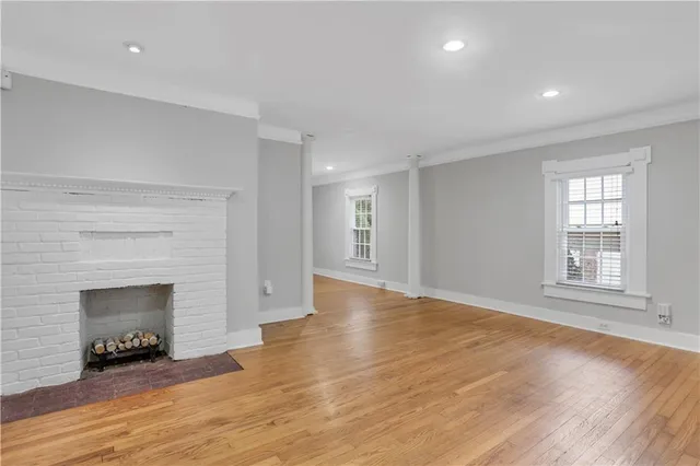 an empty room with wooden floor fireplace and windows