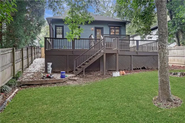 a view of a backyard with wooden fence and large trees
