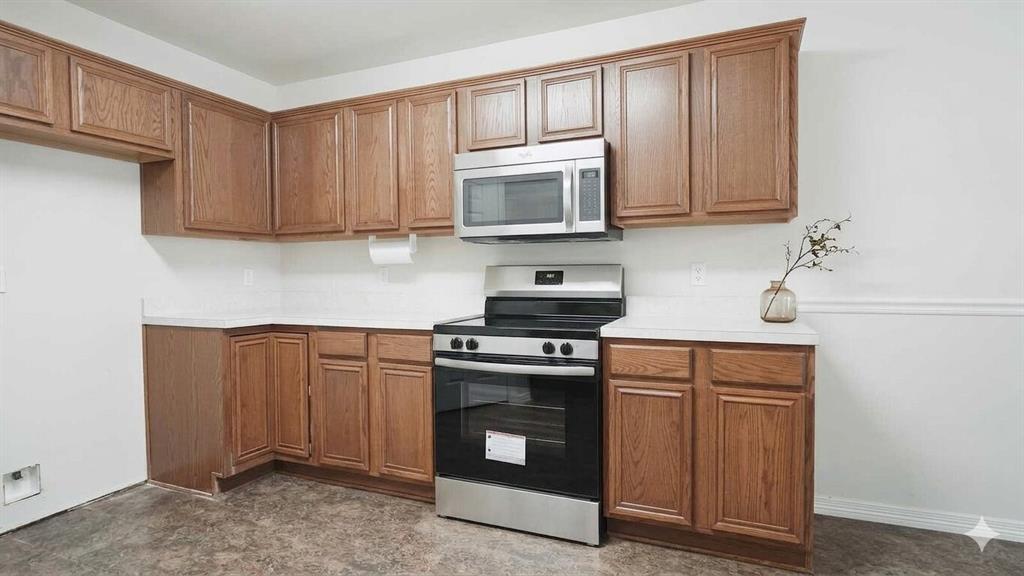 211 Vista Ridge Drive Venus, TX 76084 - Photo 10 of 24 Kitchen featuring wood-finish cabinetry, white countertops, and stainless steel appliances including a range and microwave