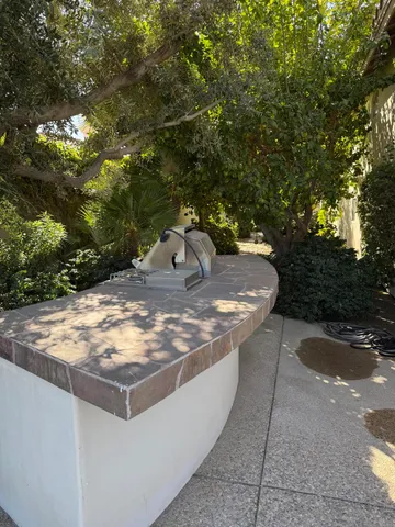 a view of a patio with couches table and chairs under an umbrella with a fire pit