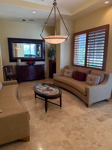 a living room with patio furniture and a chandelier