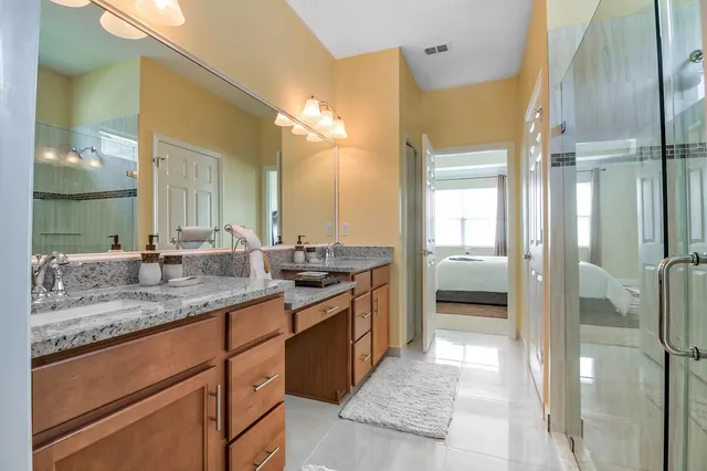 a bathroom with a granite countertop sink a mirror and a shower