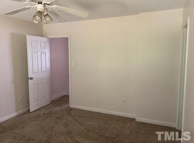 an empty room with a chandelier fan and a window