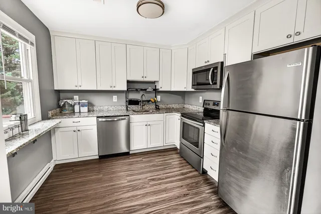 a kitchen with white cabinets stainless steel appliances and window