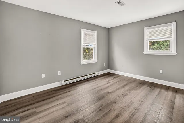 an empty room with wooden floor and windows