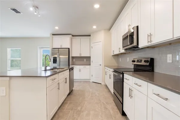 a kitchen with stainless steel appliances granite countertop a sink and dishwasher a stove top oven with white cabinets