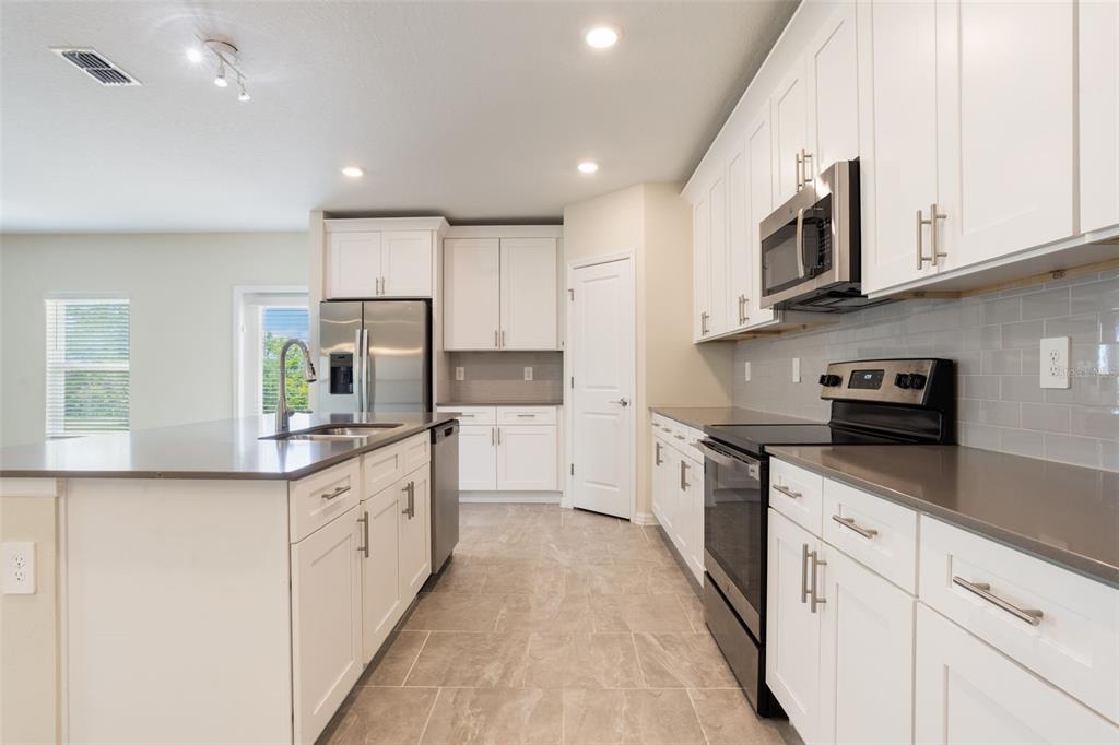 2932 Muller Oak Loop Ocoee, FL 34761 - Photo 11 of 32 a kitchen with stainless steel appliances granite countertop a sink and dishwasher a stove top oven with white cabinets