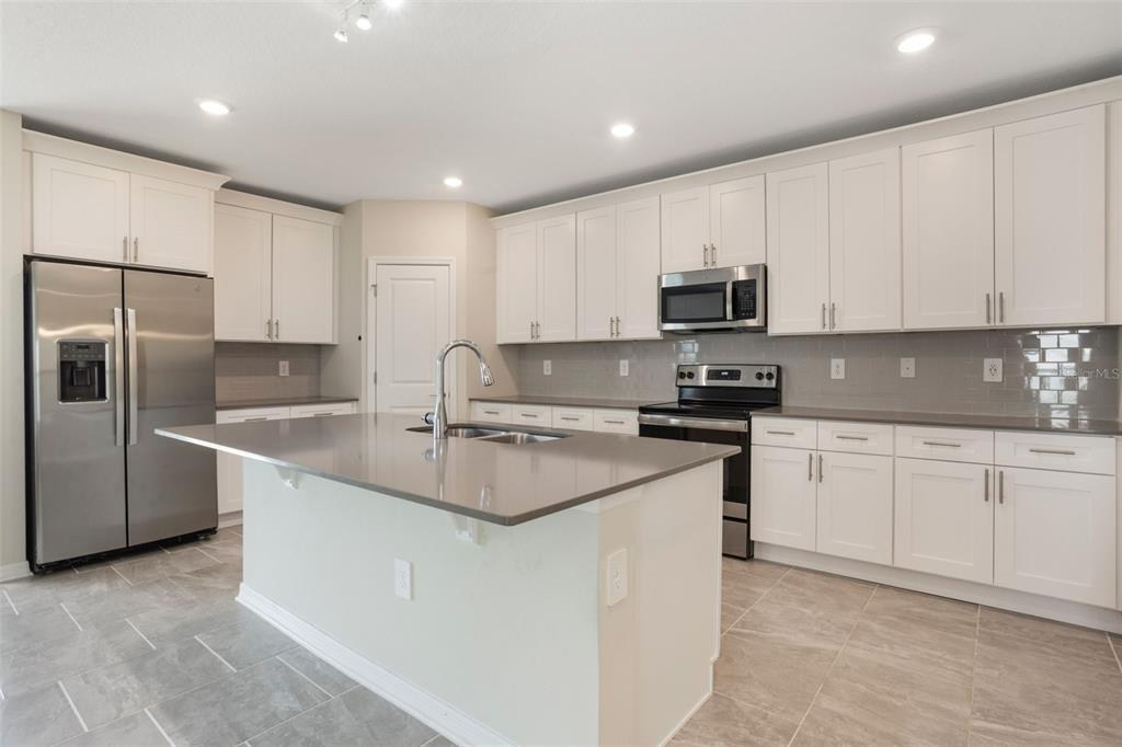 2932 Muller Oak Loop Ocoee, FL 34761 - Photo 12 of 32 a kitchen with stainless steel appliances granite countertop a sink stove and refrigerator