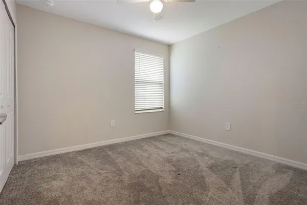 an empty room with windows and fan