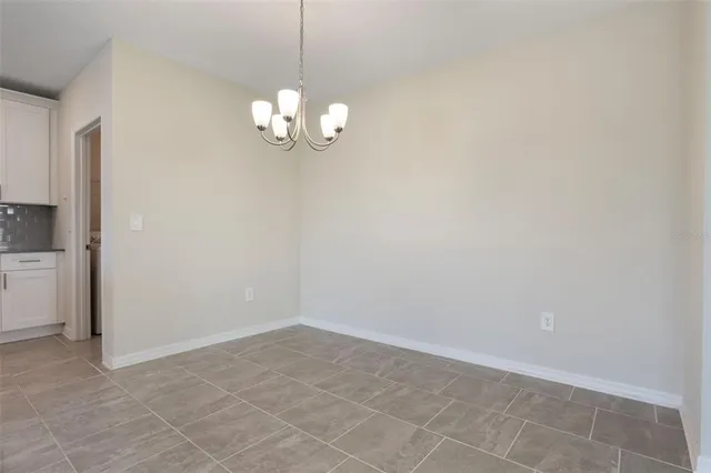a view of empty room with a chandelier fan and kitchen view