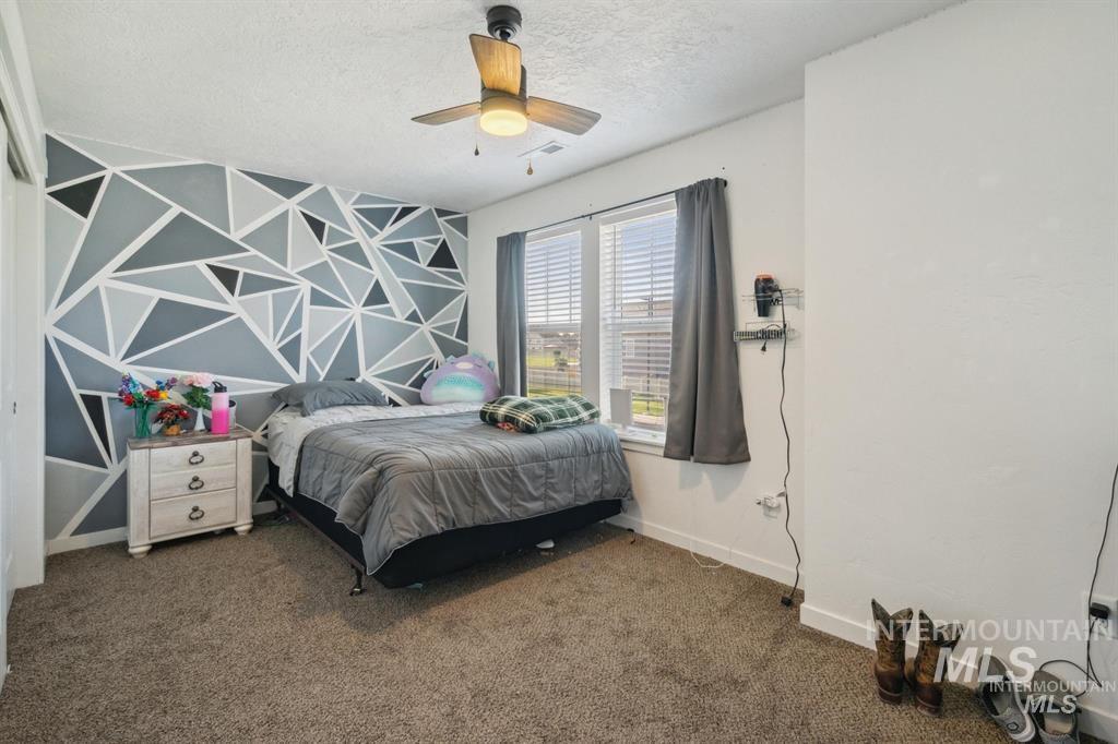 12656 Brun Street Caldwell, ID 83607 - Photo 23 of 39 Bedroom featuring an accent wall, dark carpet, a ceiling fan, and a textured ceiling