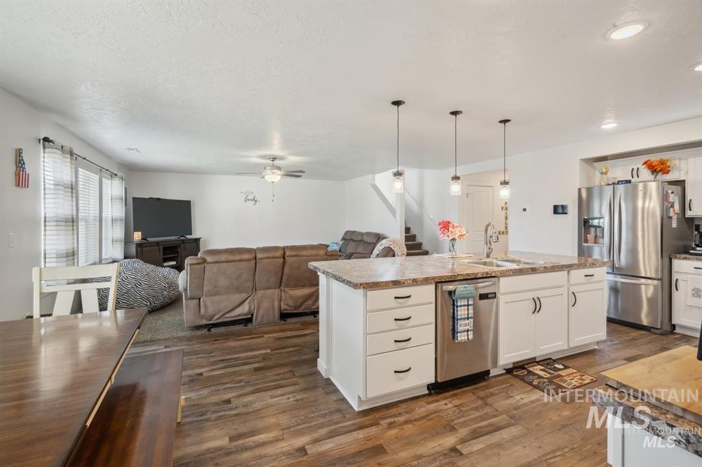 12656 Brun Street Caldwell, ID 83607 - Photo 38 of 39 Kitchen featuring white cabinetry, open floor plan, dark wood-style floors, stainless steel appliances, and hanging light fixtures