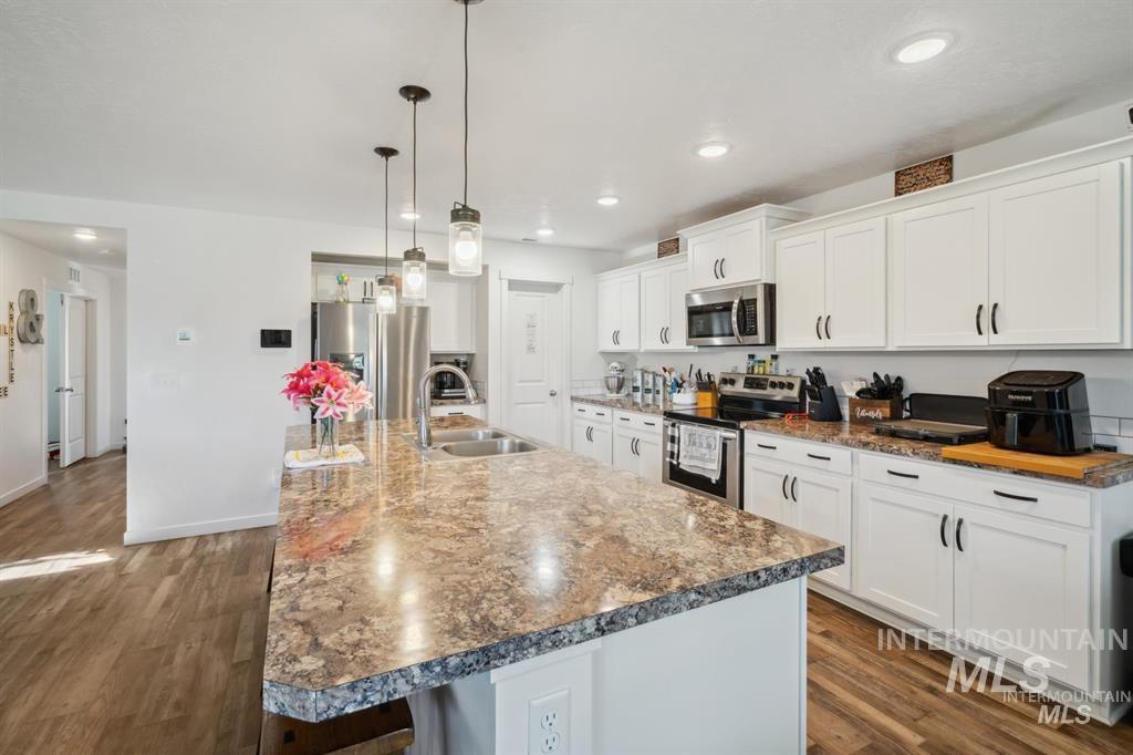 12656 Brun Street Caldwell, ID 83607 - Photo 7 of 39 Kitchen with white cabinetry, stainless steel appliances, dark wood-type flooring, and a kitchen island with sink