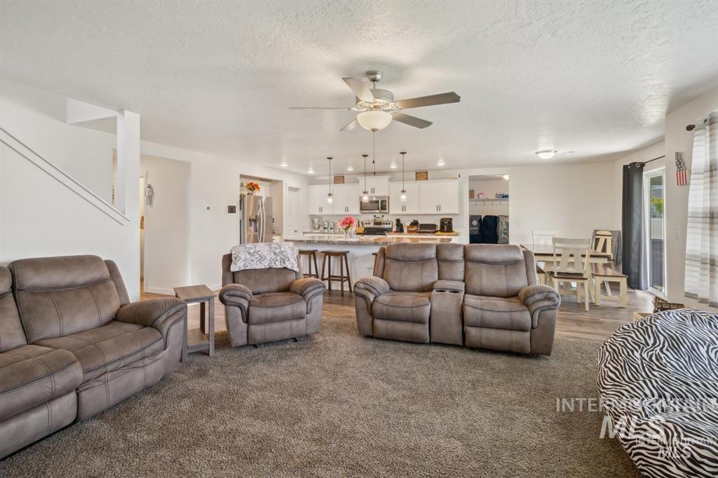 12656 Brun Street Caldwell, ID 83607 - Photo 8 of 39 Living area with ceiling fan, a textured ceiling, and dark carpet