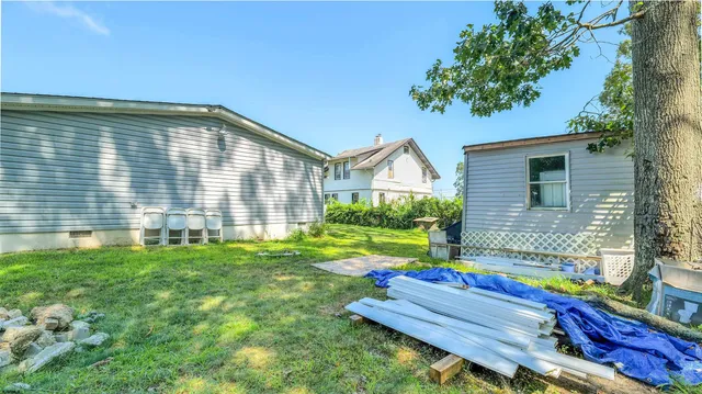 a backyard of a house with table and chairs plants and large tree