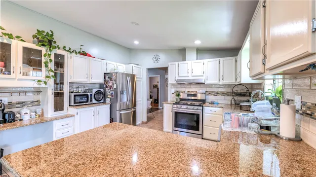 a kitchen with stainless steel appliances granite countertop a refrigerator stove top oven and sink