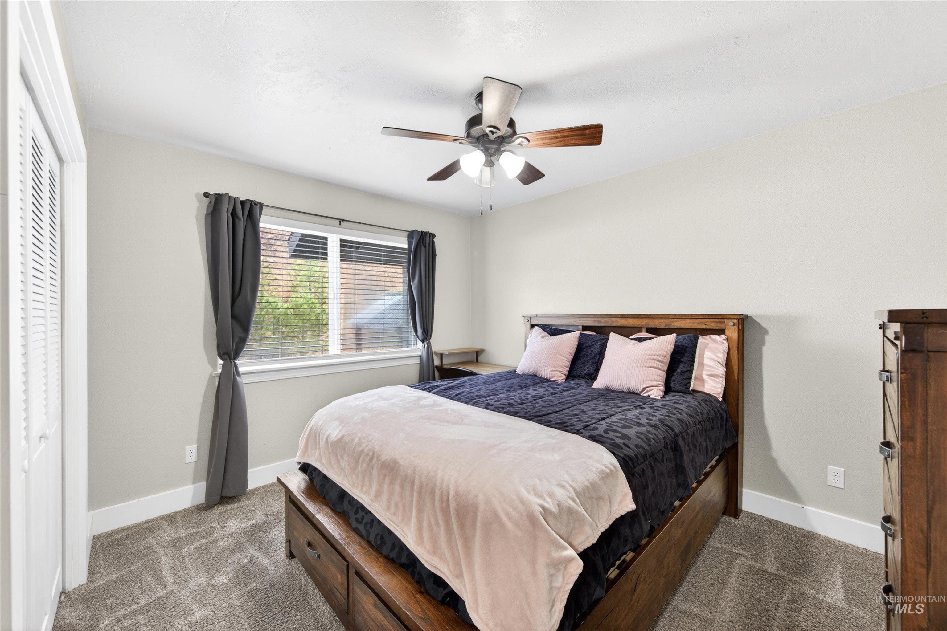 4 Round Up Circle Boise, ID 83716 - Photo 30 of 47 Room featuring neutral wall tones, carpeted flooring, a window with blinds and dark drapery, a ceiling fan with integrated lighting, and a white louvered bifold door