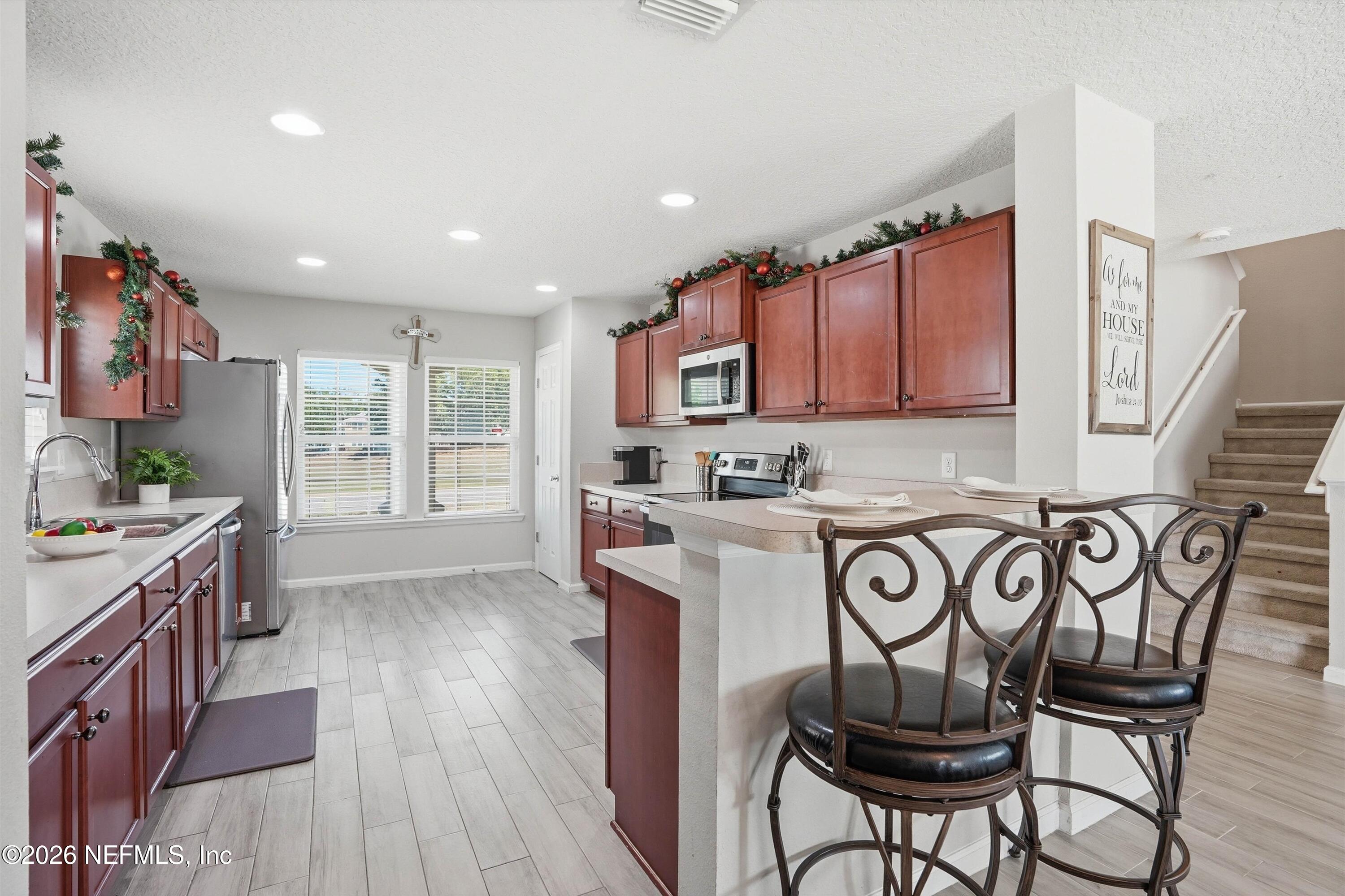 29 Auburn Oaks Road West Jacksonville, FL 32218 - Photo 9 of 38 a kitchen with stainless steel appliances granite countertop a stove top oven a sink a dining table and chairs with wooden floor
