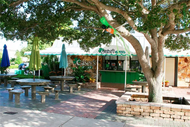 a view of a patio with table and chairs potted plants and a large tree