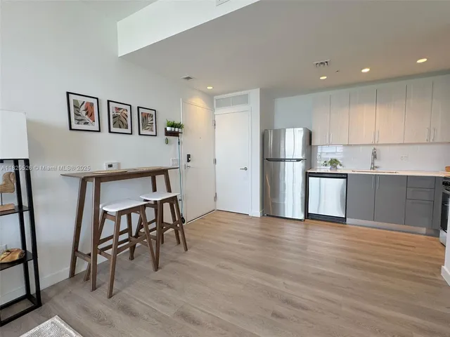 a kitchen with stainless steel appliances wooden floor and chair