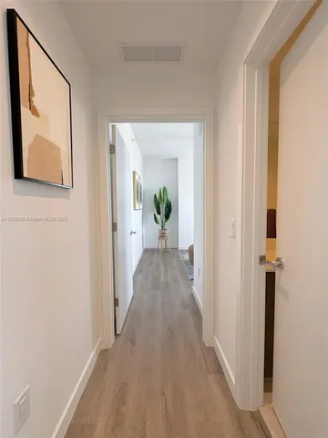 a view of a hallway with wooden floor and a living room