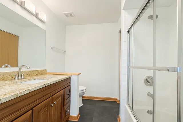 a bathroom with a granite countertop sink toilet and shower