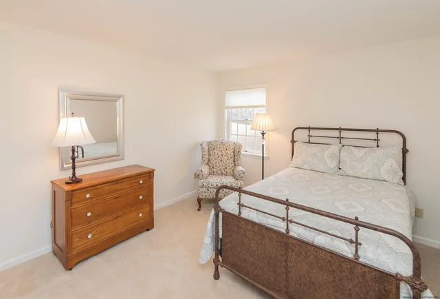 a bedroom with a bed and a lamp on dresser
