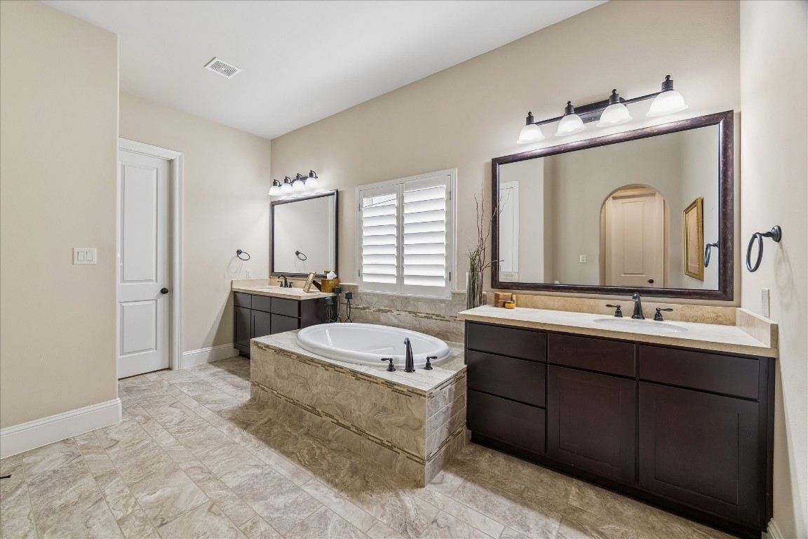 3 Tiburon Court Spring, TX 77389 - Photo 17 of 35 This elegant bathroom features a spacious layout with dual sinks, a luxurious soaking tub, and stylish dark wood cabinetry. The neutral tile flooring and soft lighting create a relaxing atmosphere.