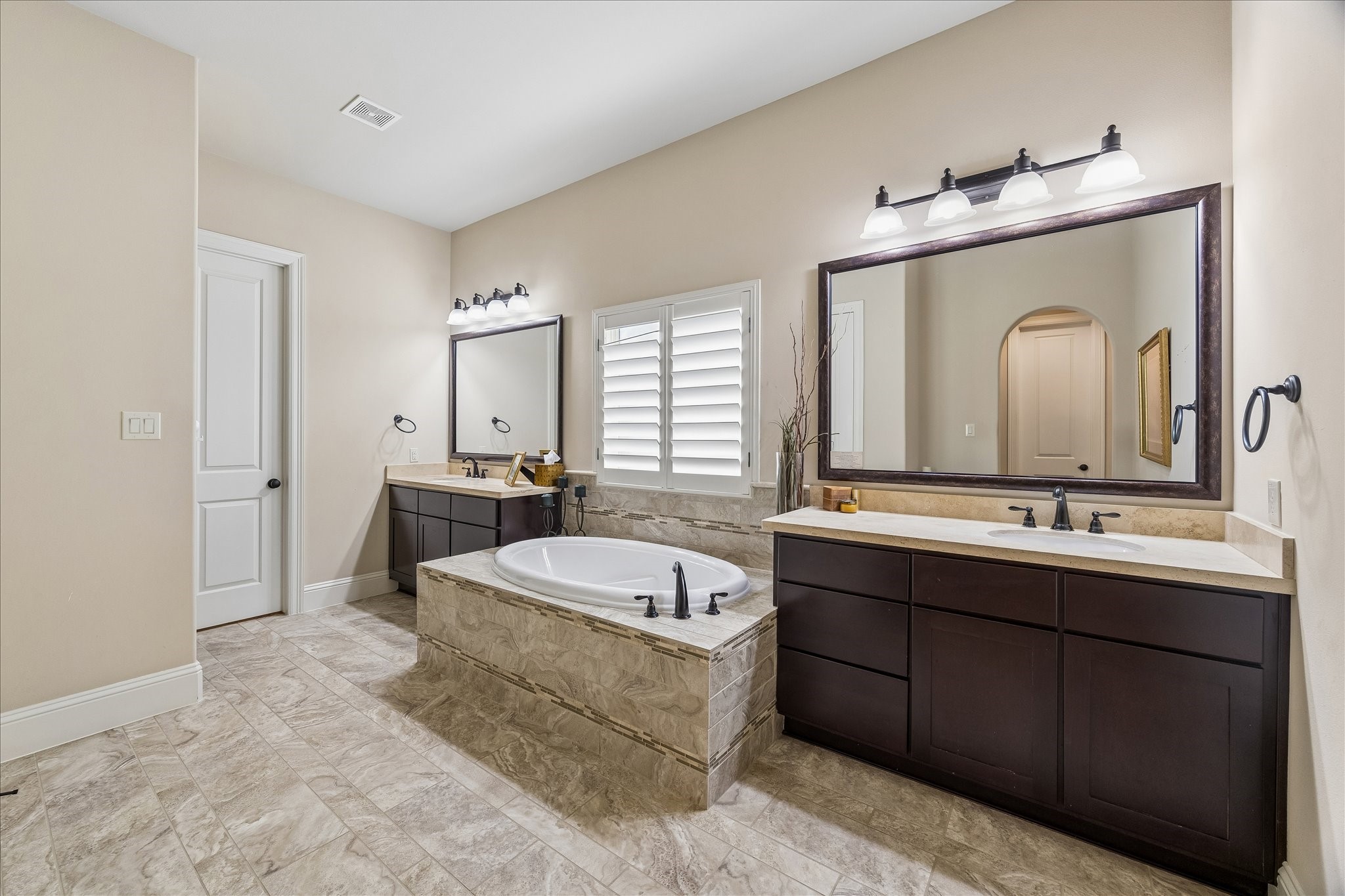 3 Tiburon Court Spring, TX 77389 - Photo 17 of 37 This elegant bathroom features a spacious layout with dual sinks, a luxurious soaking tub, and stylish dark wood cabinetry. The neutral tile flooring and soft lighting create a relaxing atmosphere.