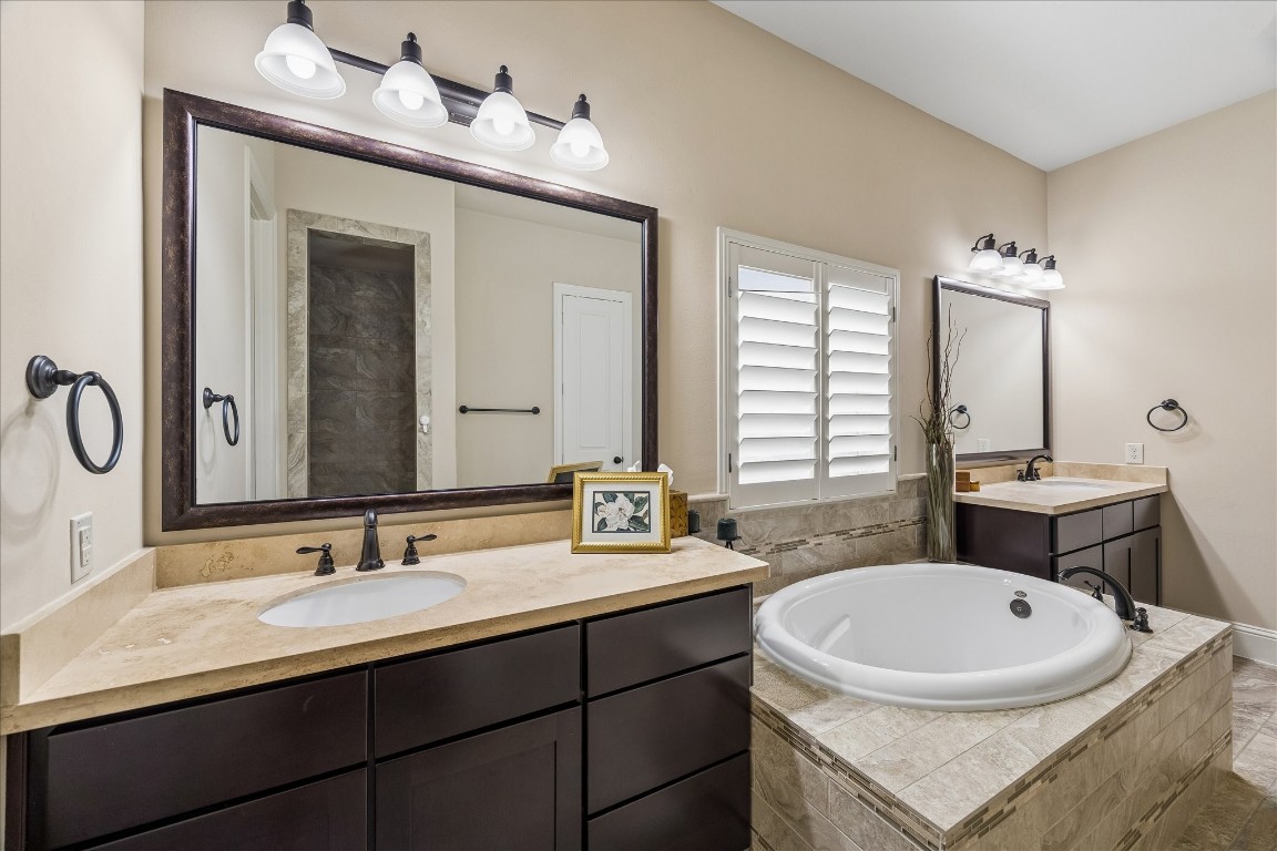 3 Tiburon Court Spring, TX 77389 - Photo 18 of 35 This bathroom features a spacious layout with a central soaking tub, dual sinks with dark wood cabinets, elegant stone countertops, and contemporary light fixtures.