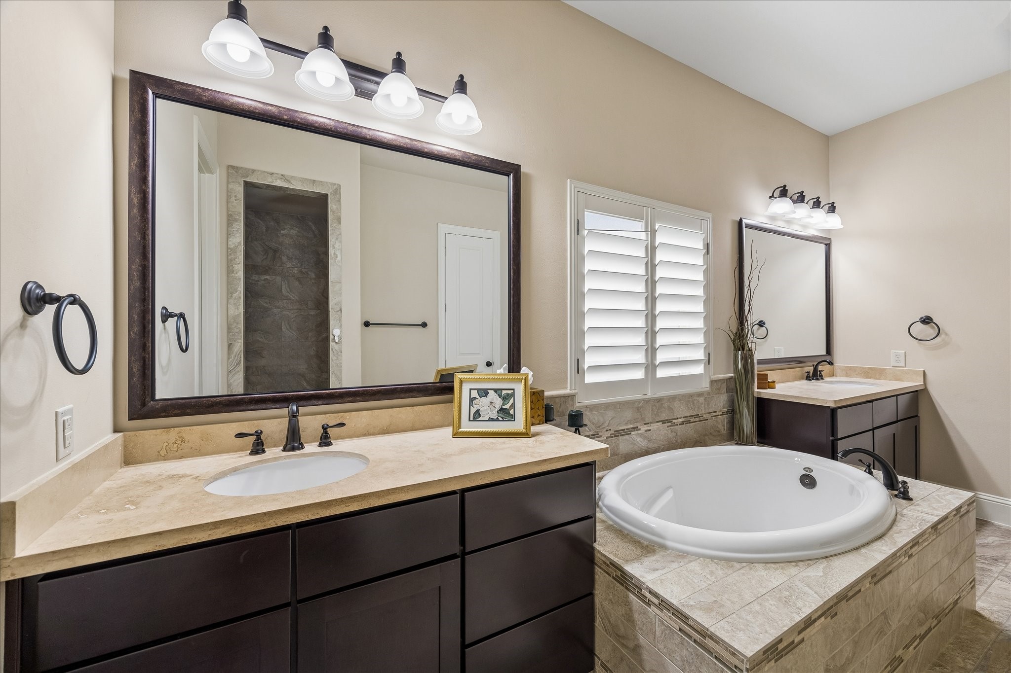 3 Tiburon Court Spring, TX 77389 - Photo 18 of 37 This bathroom features a spacious layout with a central soaking tub, dual sinks with dark wood cabinets, elegant stone countertops, and contemporary light fixtures.