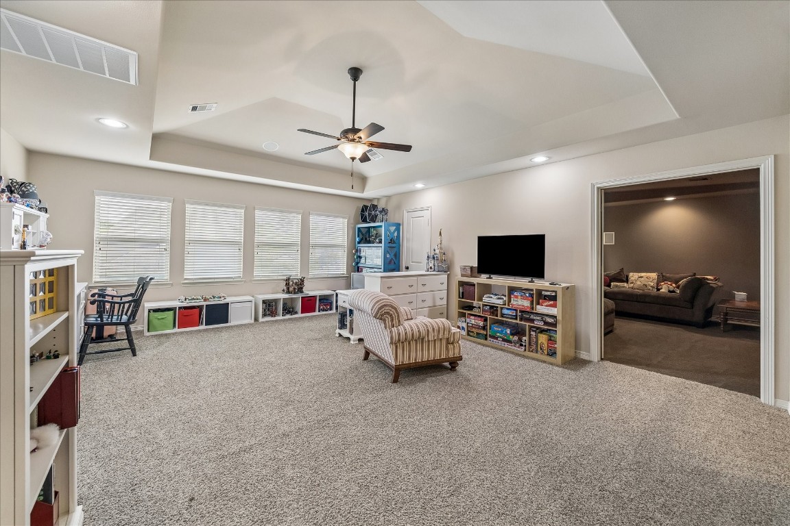 3 Tiburon Court Spring, TX 77389 - Photo 19 of 35 This spacious, carpeted family room features large windows for natural light, a ceiling fan, and ample storage. It's connected to a cozy entertainment area, making it ideal for relaxation and play.