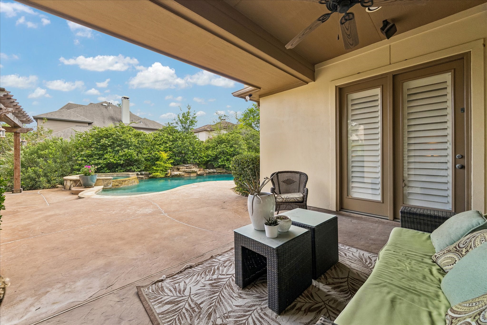 3 Tiburon Court Spring, TX 77389 - Photo 27 of 37 Cozy backyard patio with comfortable seating, overlooking a beautiful pool surrounded by lush greenery. It offers a perfect space for relaxation and outdoor enjoyment.
