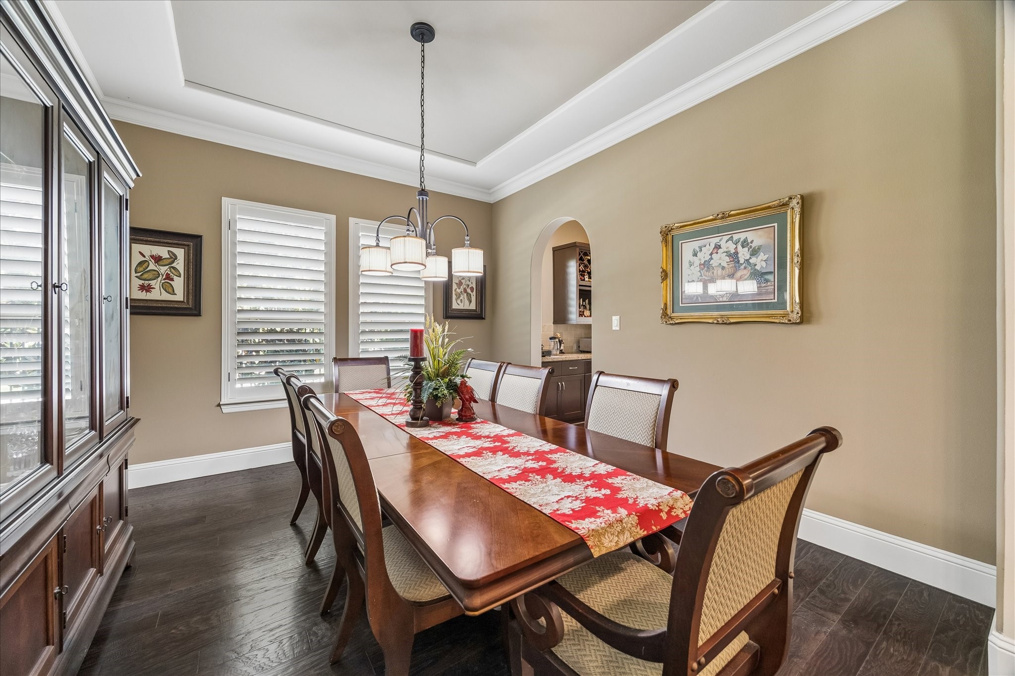 3 Tiburon Court Spring, TX 77389 - Photo 9 of 37 The dining room features elegant tray ceilings, hardwood floors, and ample natural light from large windows with plantation shutters. A decorative archway leads to the butler's pantry, enhancing its charm.