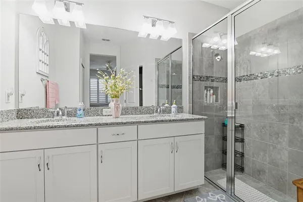 a bathroom with a granite countertop sink a mirror and a shower