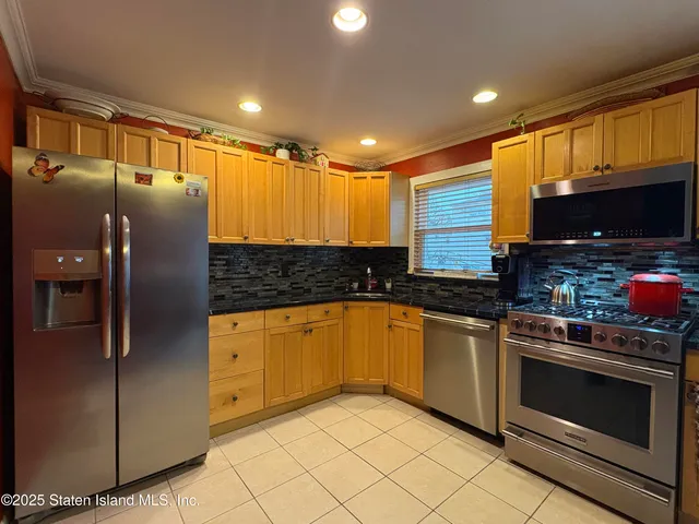 a kitchen with stainless steel appliances granite countertop a refrigerator a stove and a sink