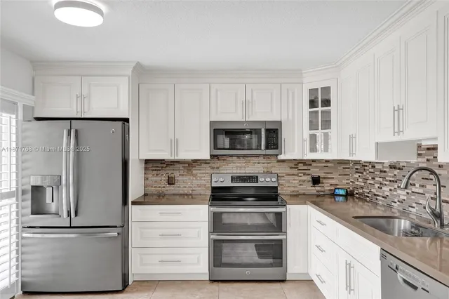 a kitchen with white cabinets and stainless steel appliances