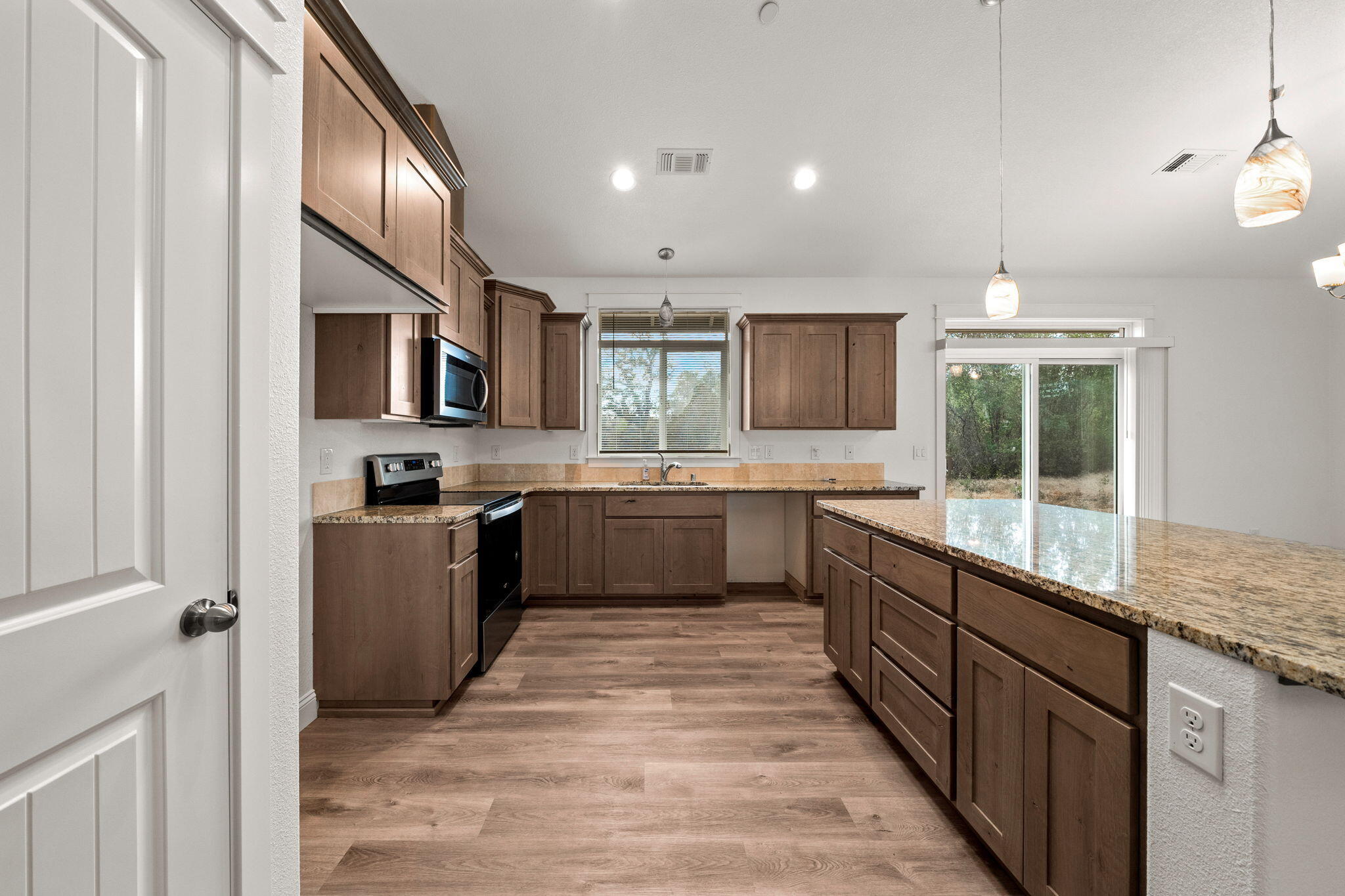 7590 Hopeful Place Shingletown, CA 96088 - Photo 8 of 31 a large kitchen with stainless steel appliances granite countertop a stove top oven a sink dishwasher a dining table and chairs with wooden floor