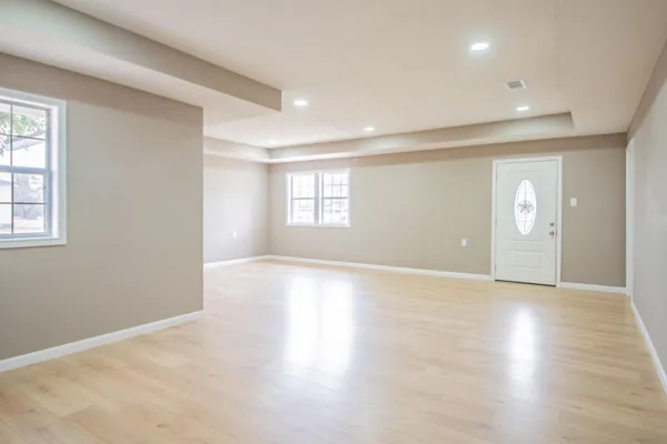 an empty room with wooden floor and windows