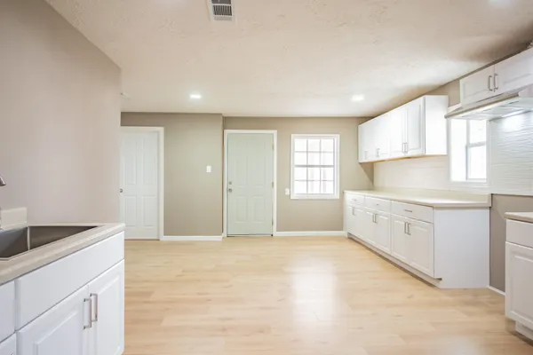 a large white kitchen with granite countertop white cabinets and white appliances