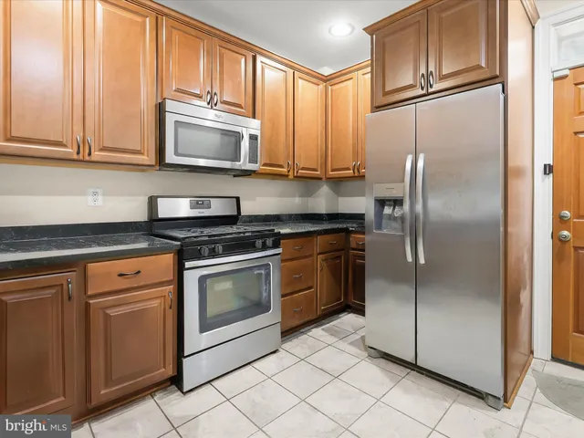 a kitchen with granite countertop white cabinets stainless steel appliances and a window