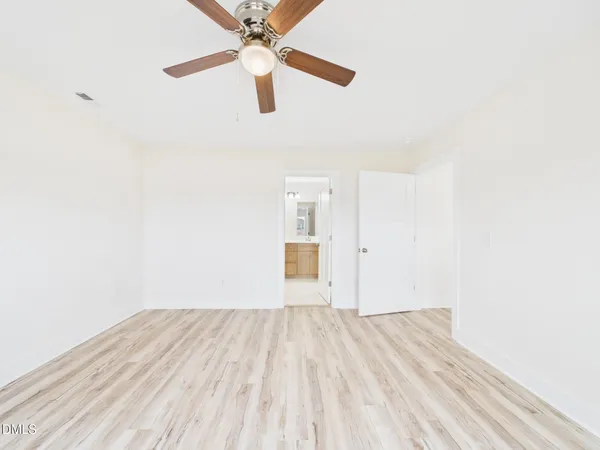 a view of a room with wooden floor and a ceiling fan